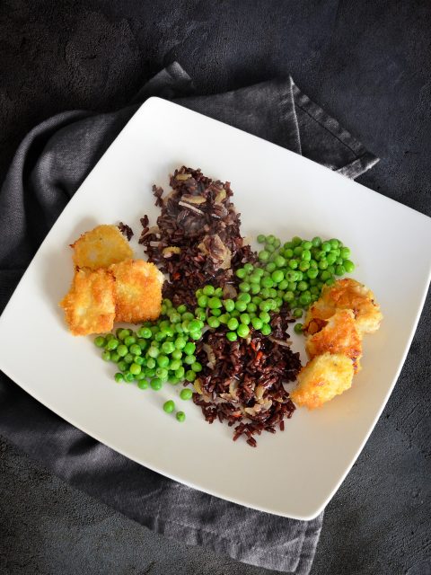 Chicken Nuggets mit Erbsen auf schwarzem Reis mit Sellerie