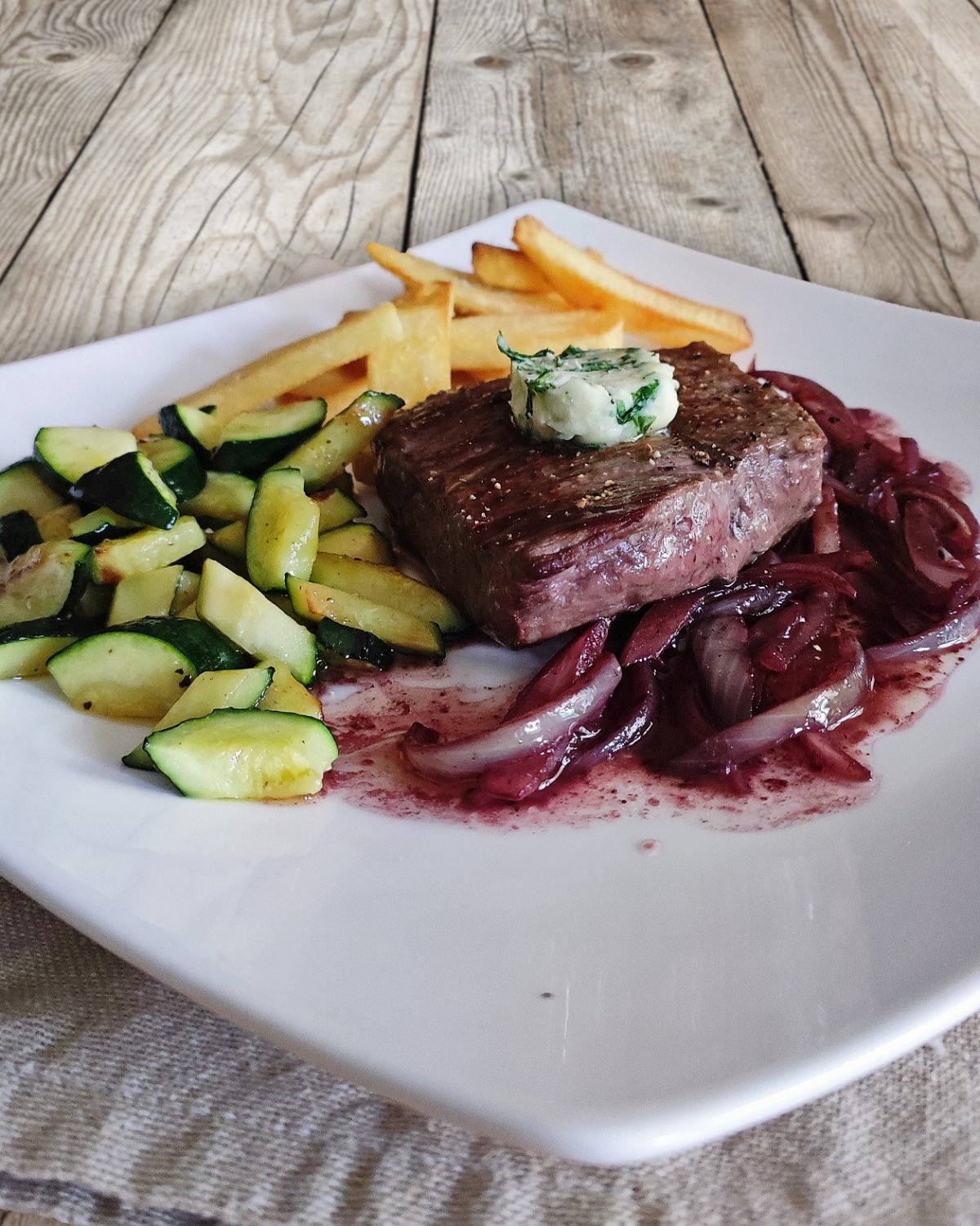 Steak mit Rotwein-Zwiebel-Sauce, Zucchini und Pommes