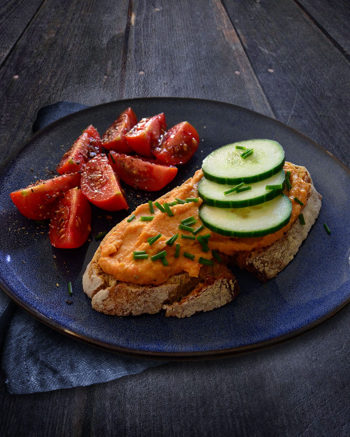 Frühstück mit frisch gebackenem Sauerteigbrot, Paprikahummus, Gurken und Tomaten