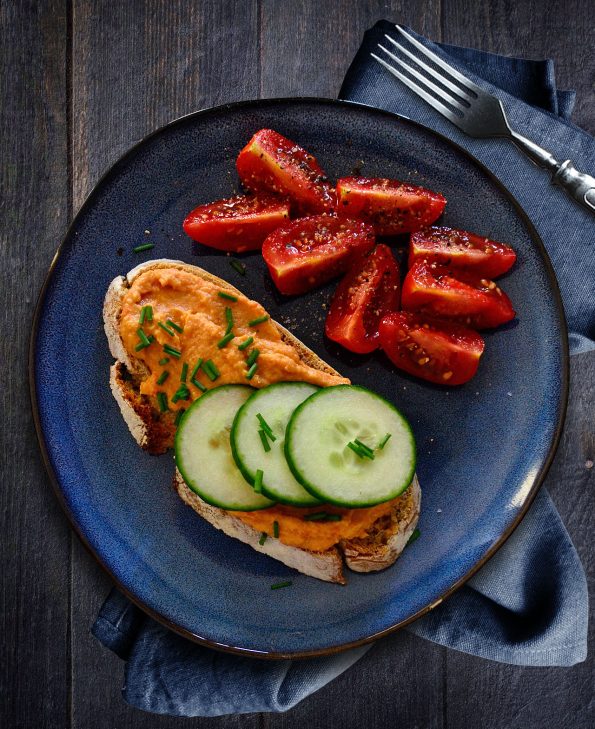 Frühstück mit frisch gebackenem Sauerteigbrot, Paprikahummus, Gurken und Tomaten