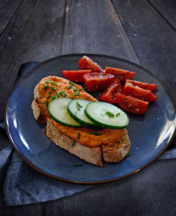 Frühstück mit frisch gebackenem Sauerteigbrot, Paprikahummus, Gurken und Tomaten