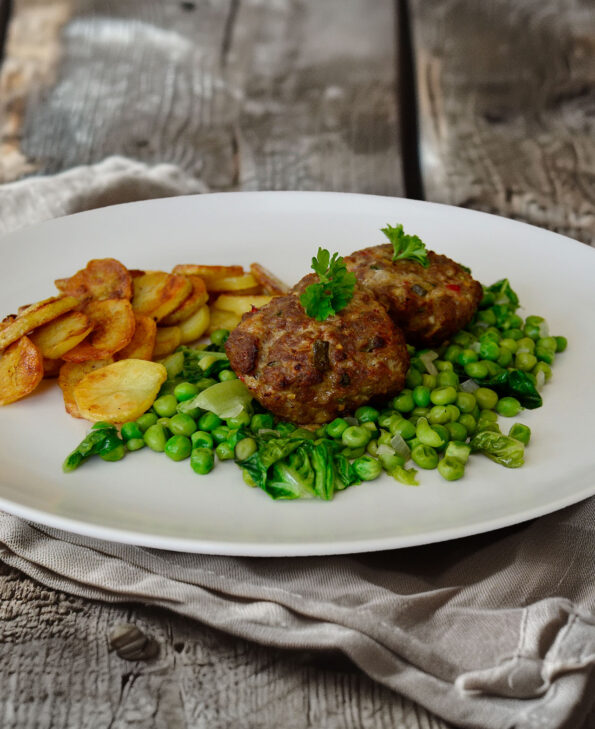 Frikadellen auf französischen Erbsen mit Bratkartoffeln