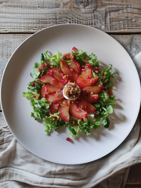 Ziegenkäsetaler mit Honig-Speck-Crumble auf Blattsalat mit Granatapfel-Dressing und Pflaumen-Carpaccio