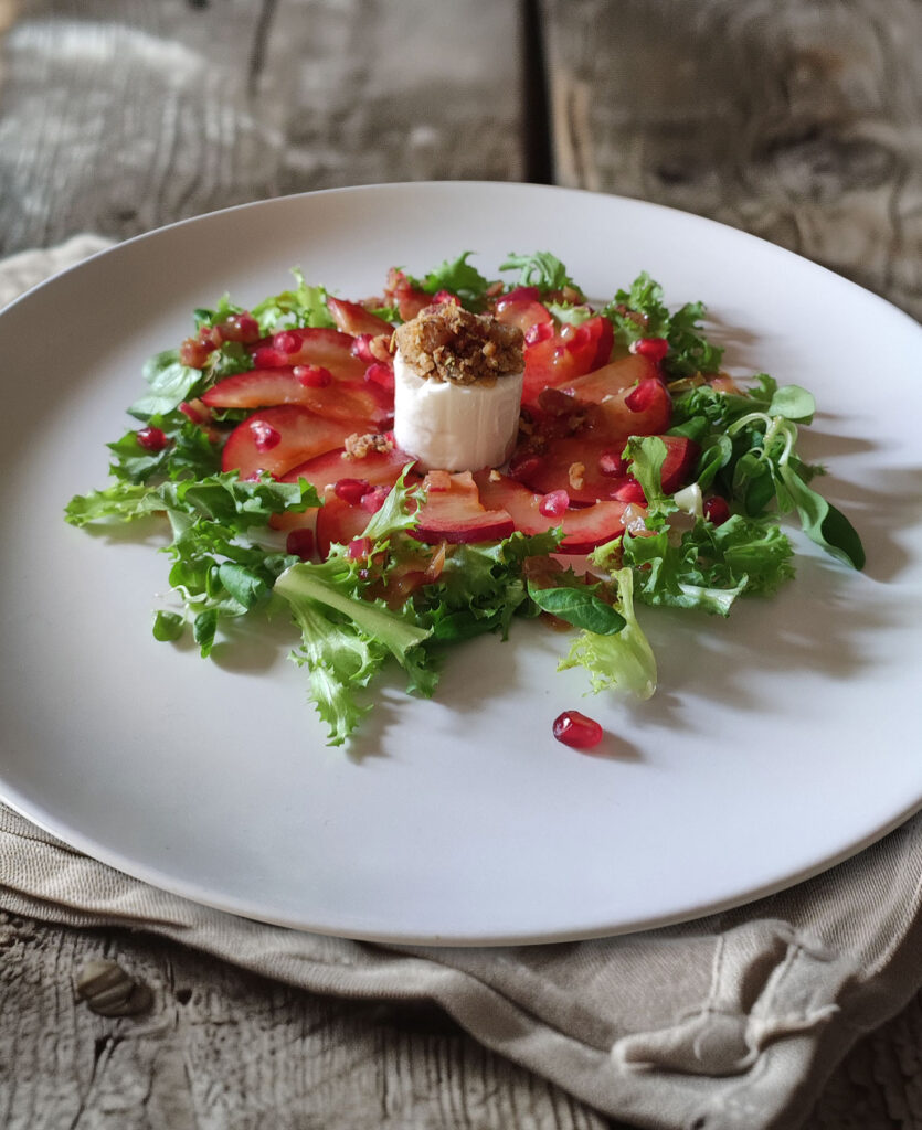 Ziegenkäsetaler mit Honig-Speck-Crumble auf Blattsalat mit Granatapfel-Dressing und Pflaumen-Carpaccio