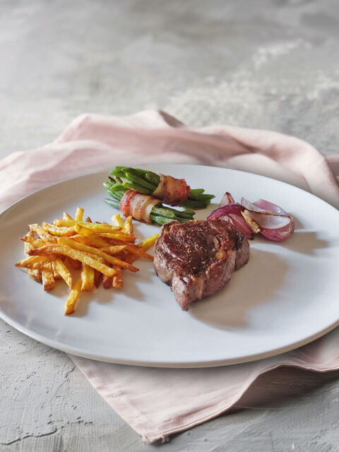 Rib Eye Steak mit Bohnen im Speckmantel, Zwiebeln und Pommes